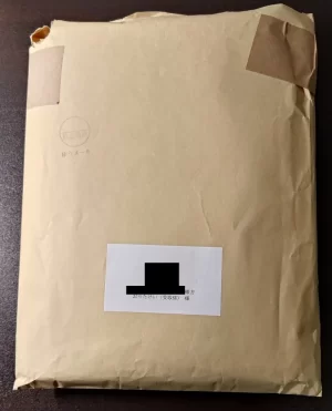 A4サイズの茶封筒。書籍が一冊入っていて少し膨らんでいる。Amazonのマーケットプレイス出品者から購入した商品で、Amazonの段ボールで配送されないことを説明している